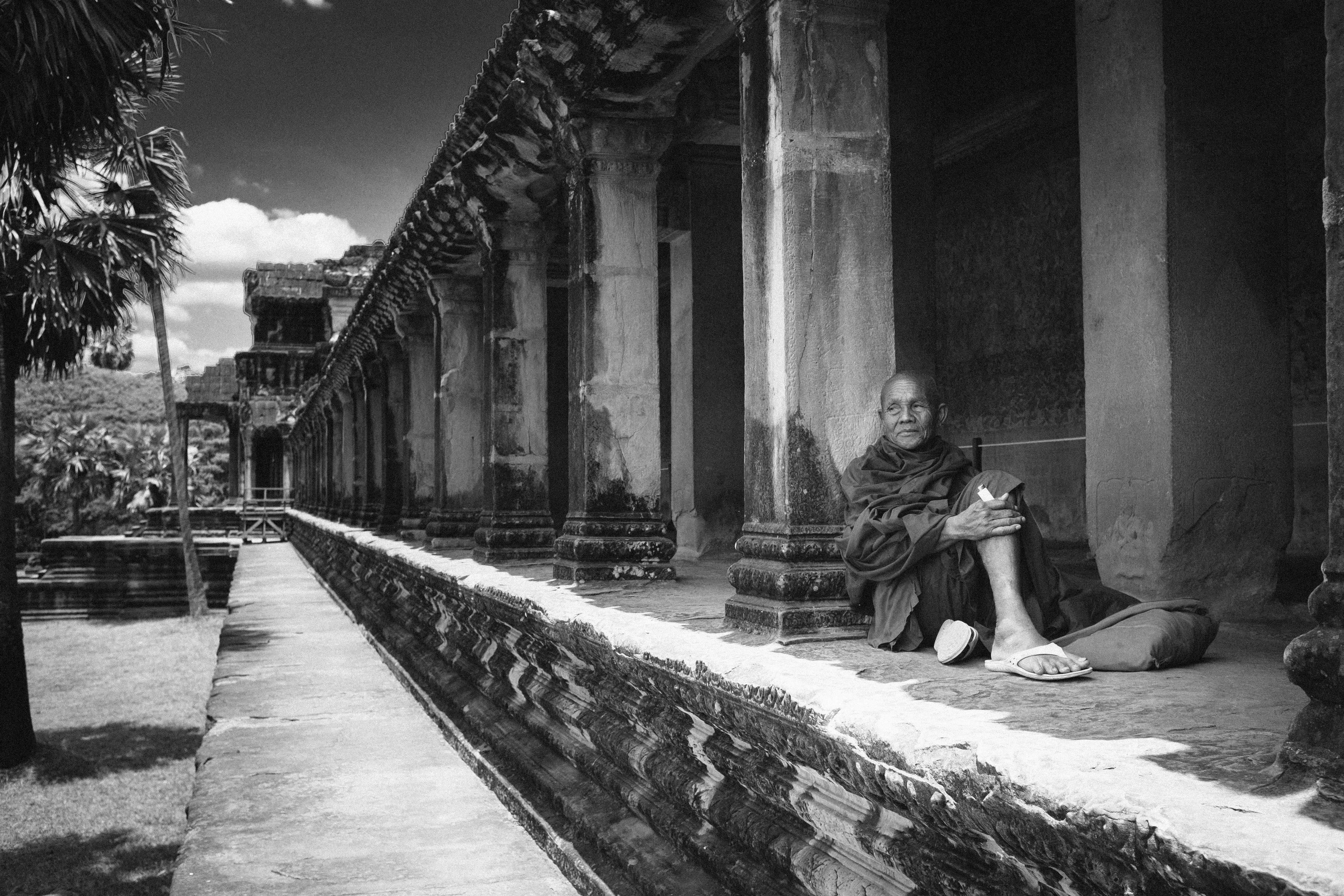 grayscale photo of woman sitting on concrete bench, 