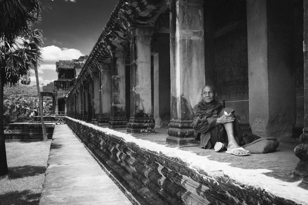 grayscale photo of woman sitting on concrete bench