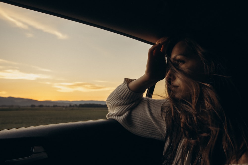 woman in white and black striped long sleeve shirt sitting on car seat during daytime