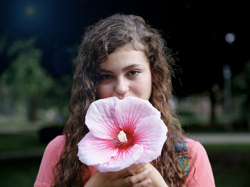 girl in pink shirt holding pink hibiscus flower