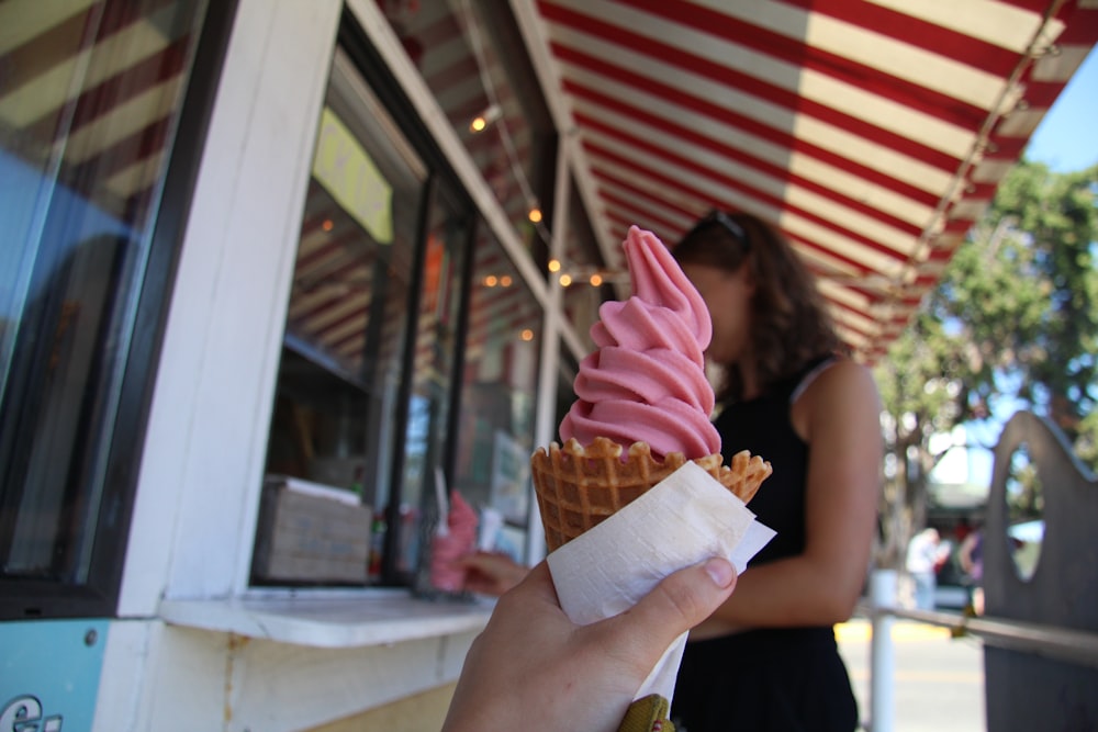 woman in pink tank top holding ice cream cone