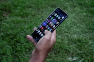 Hands holding a smartphone displaying an app for real-time farm monitoring.