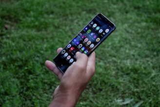 A vibrant hands holding a smartphone with colorful game icons on the screen.