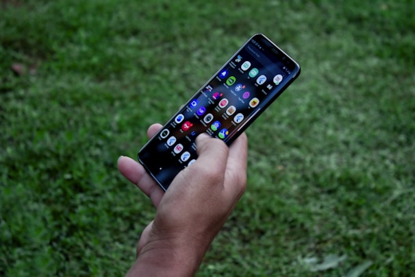 A vibrant hands holding a smartphone with colorful game icons on the screen.