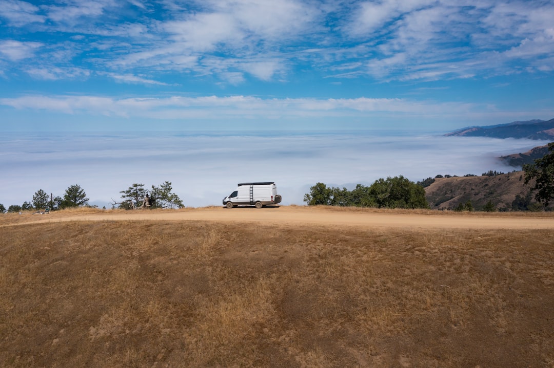 white van on brown field under blue sky during daytime