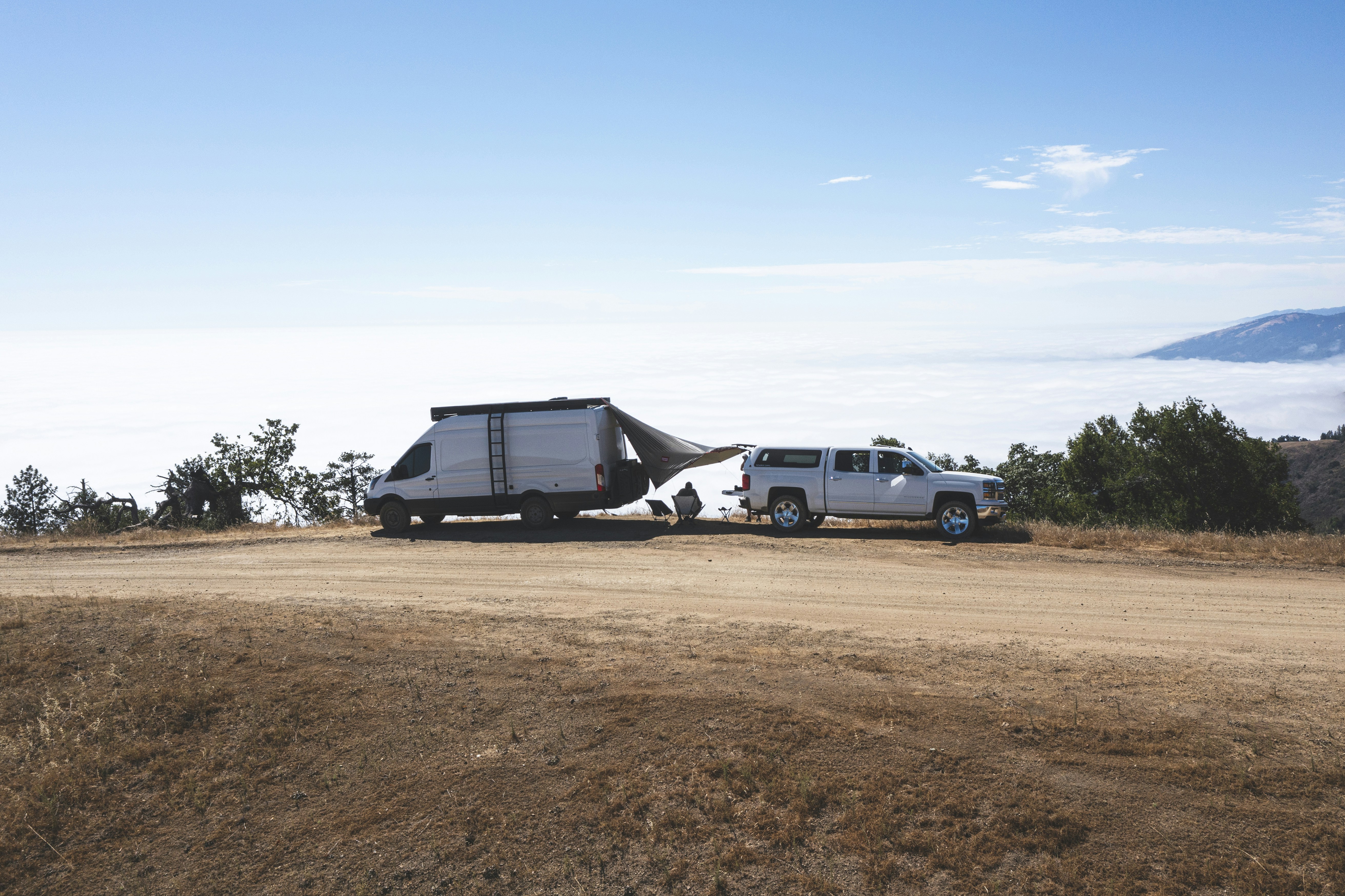 white crew cab pickup truck parked beside white and black house under blue sky during daytime