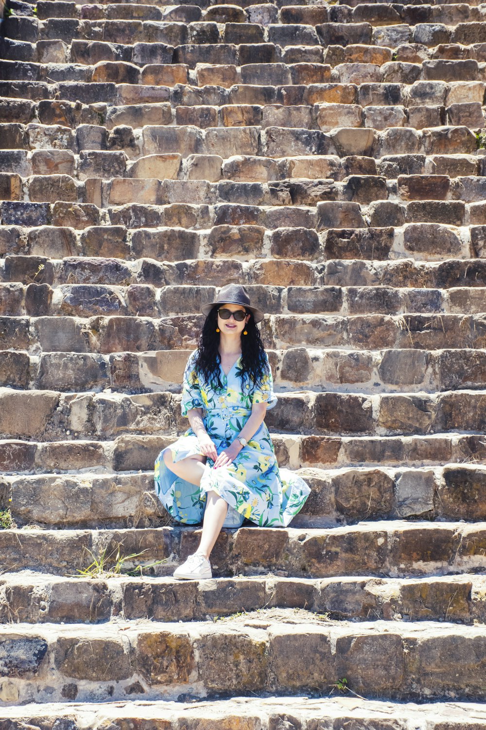 woman in red and yellow floral dress standing on brown brick wall during daytime