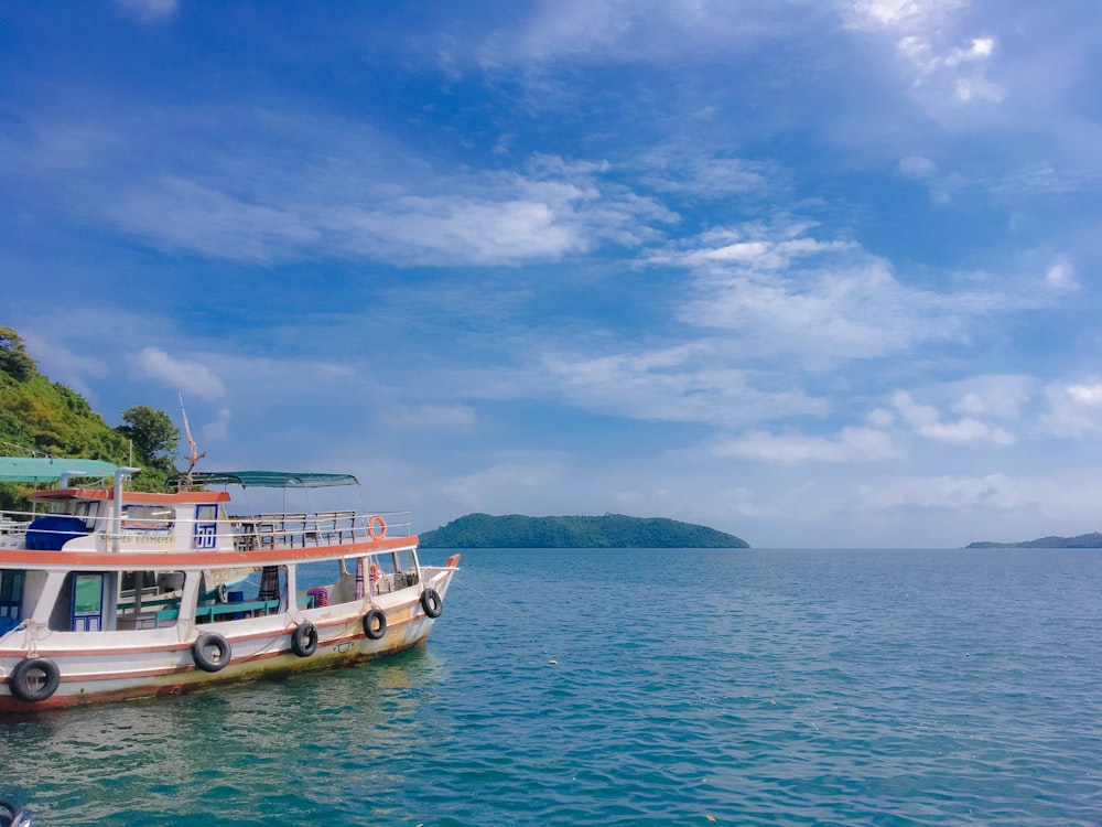 white and blue boat on sea under cloudy sky during daytime