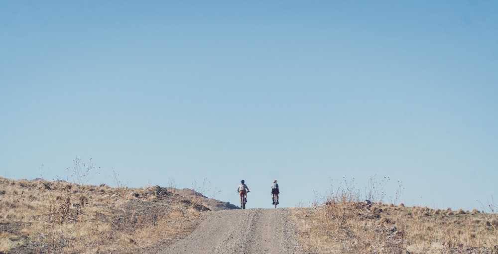 man in black jacket and black pants walking on brown dirt road during daytime