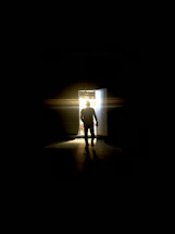 A silhouette of a man stepping from shadow into bright light, symbolizing hope and freedom.