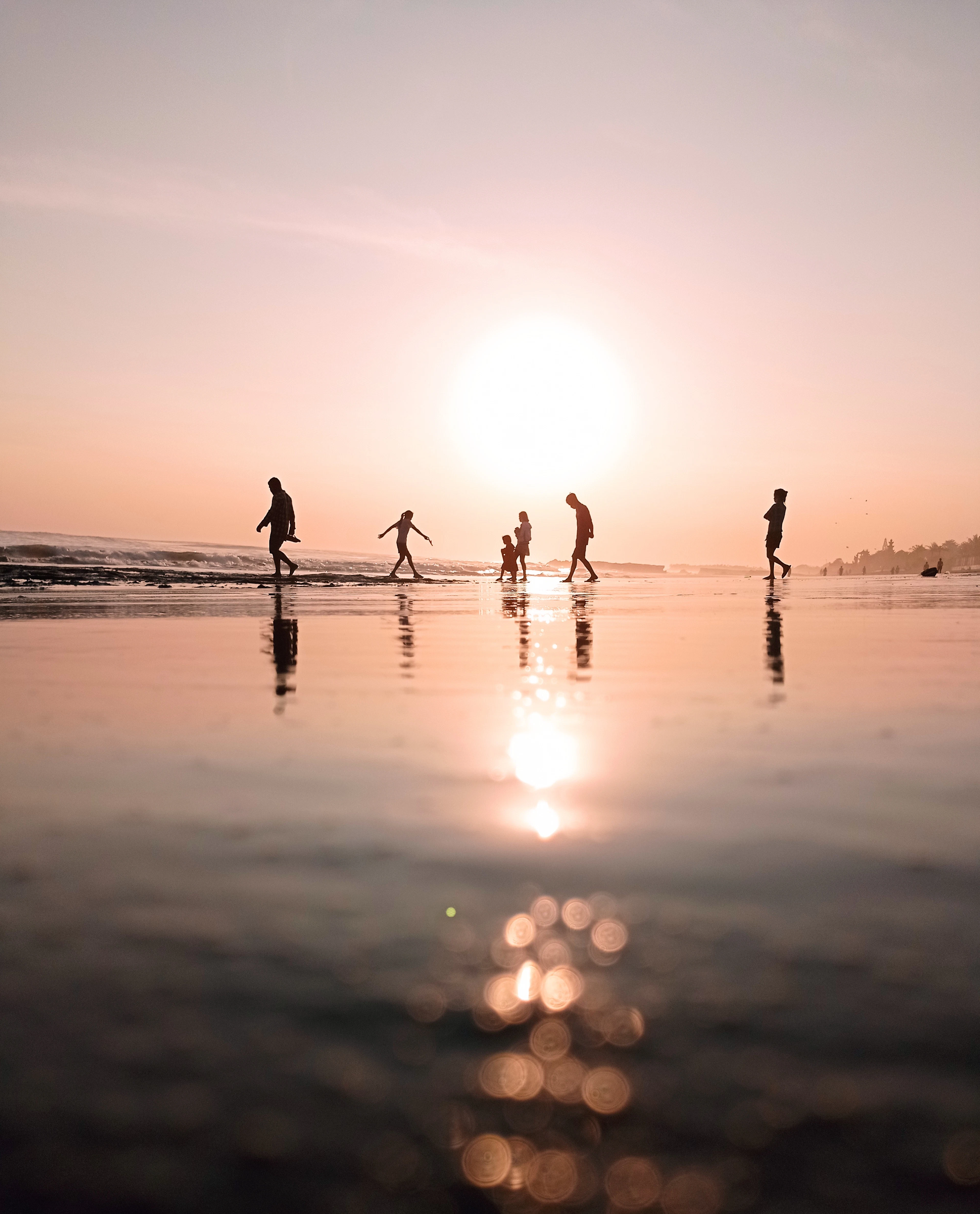Silhouettes walking along the shore at sunset