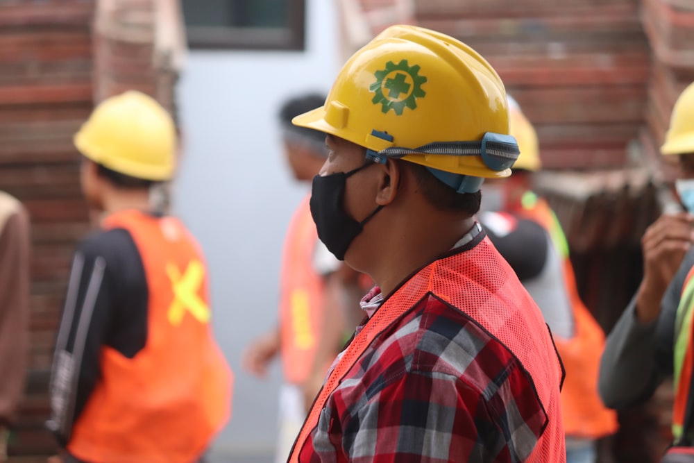 homem na camisa xadrez vermelha azul e branca vestindo o capacete amarelo