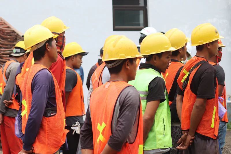 Pekerja pabrik mengenakan alat pelindung diri dan helm