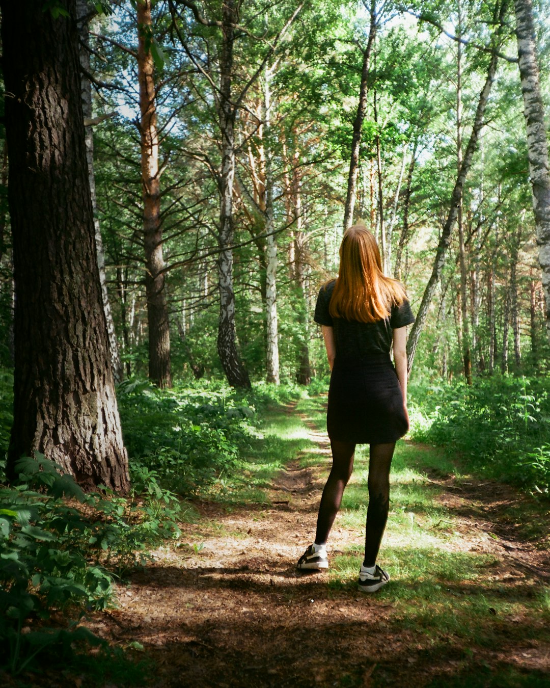woman in black dress standing on forest during daytime