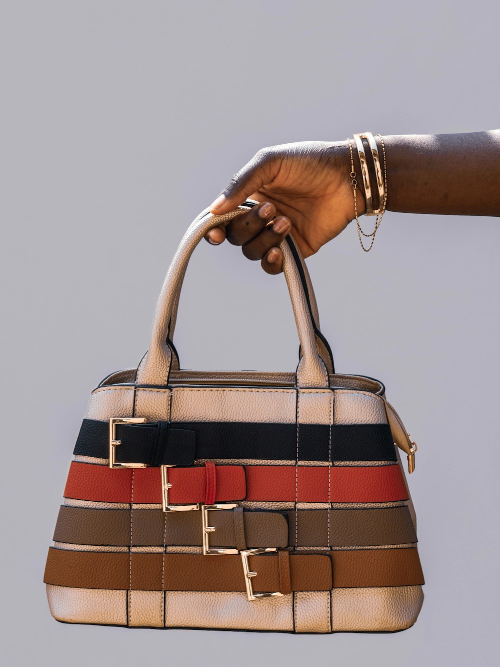 person holding black red and white plaid handbag