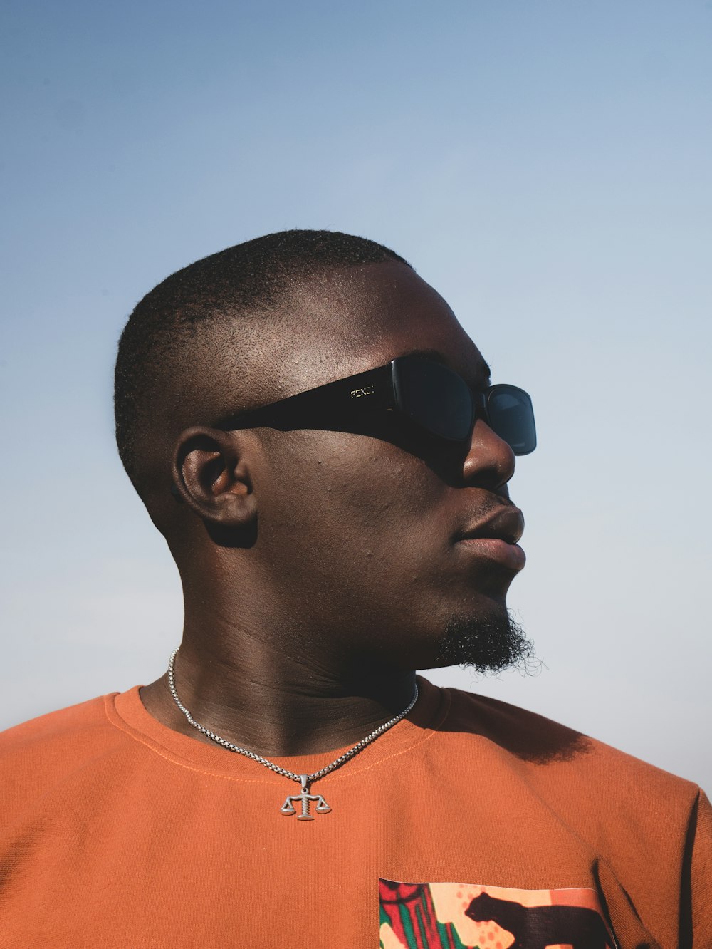 man in orange crew neck shirt wearing black sunglasses