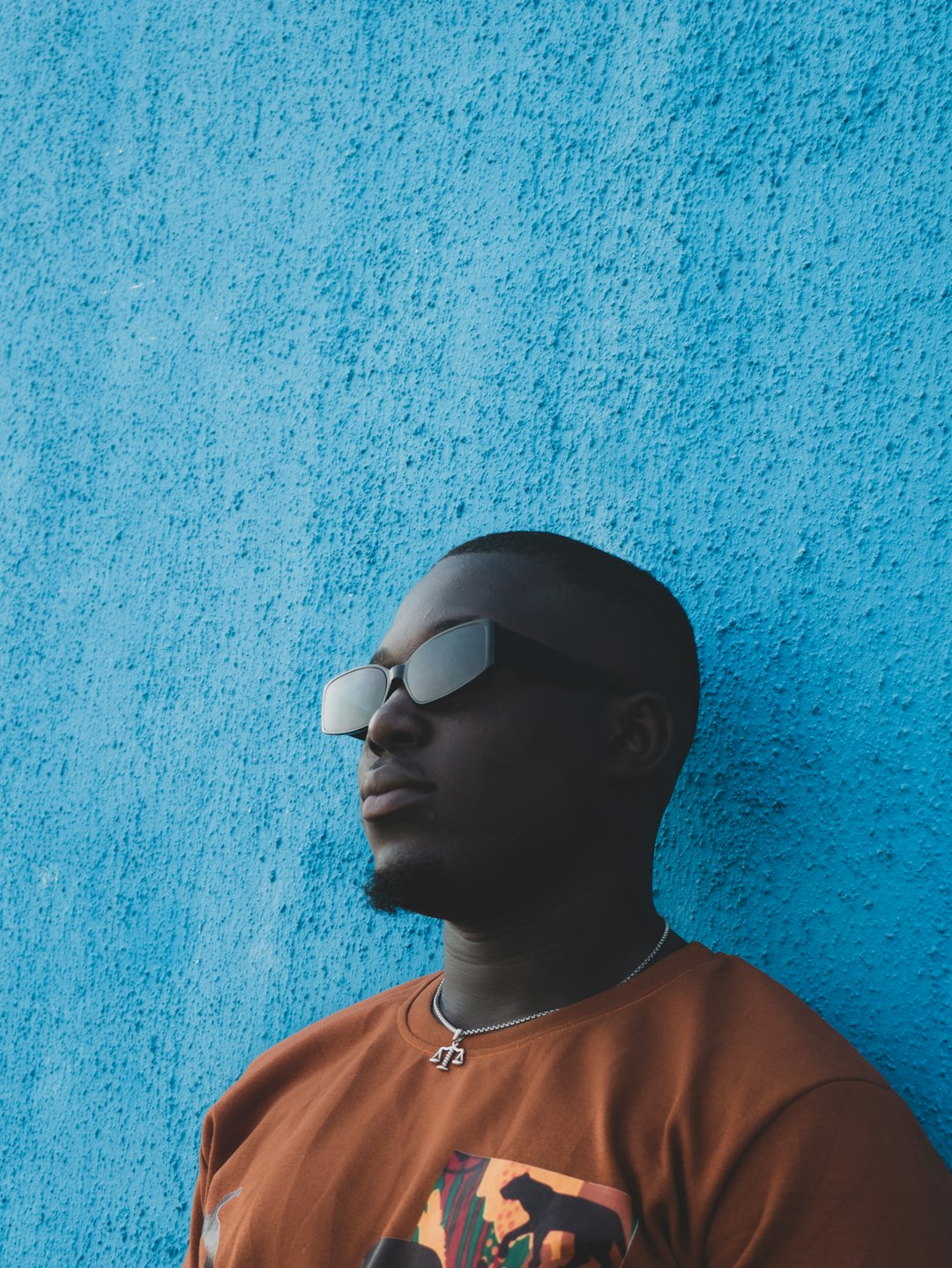 man in orange crew neck shirt wearing black sunglasses