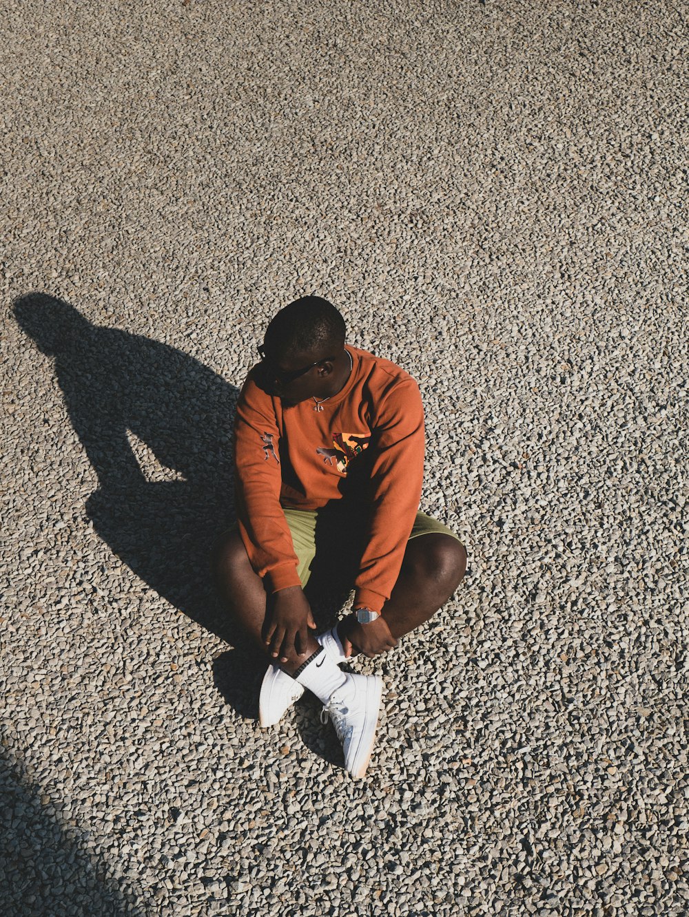 man in orange t-shirt and black pants sitting on floor