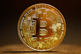 a golden bitcoin sitting on top of a table