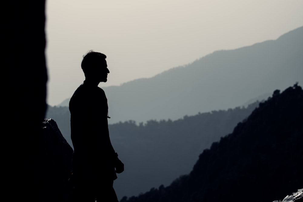 silhouette d’homme debout au sommet de la montagne pendant la journée