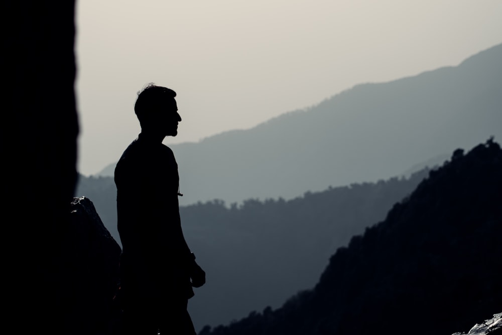 silhouette dell'uomo in piedi sulla cima della montagna durante il giorno