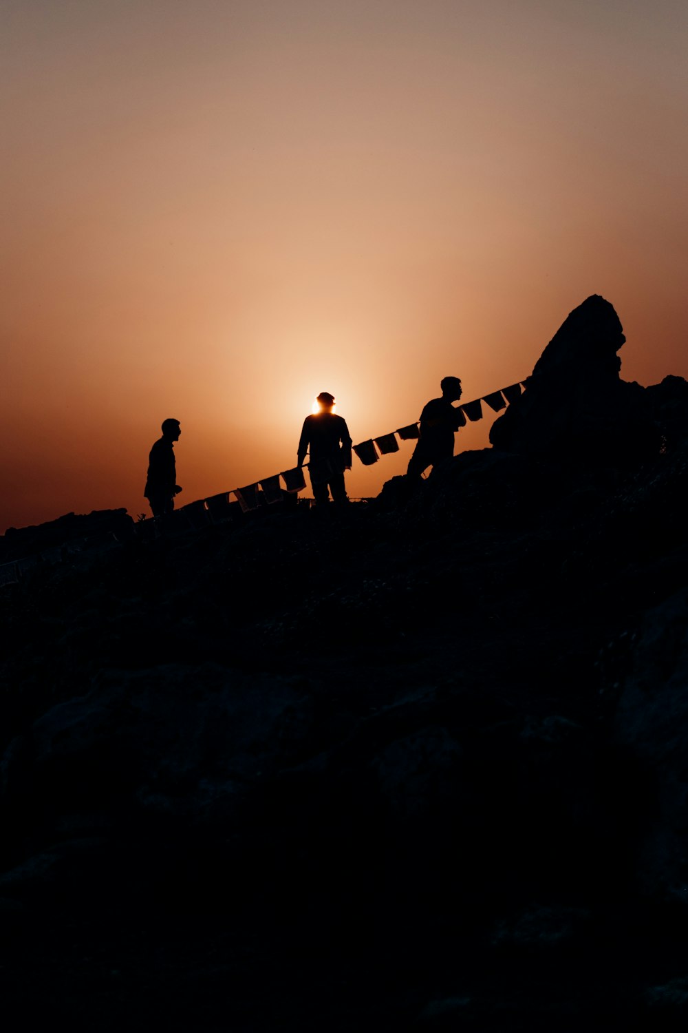 夕暮れ時の岩層に立つ人々のシルエット