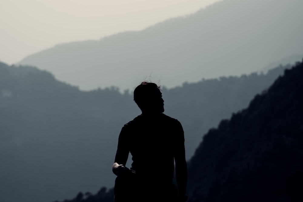 man in black shirt standing on top of mountain during daytime