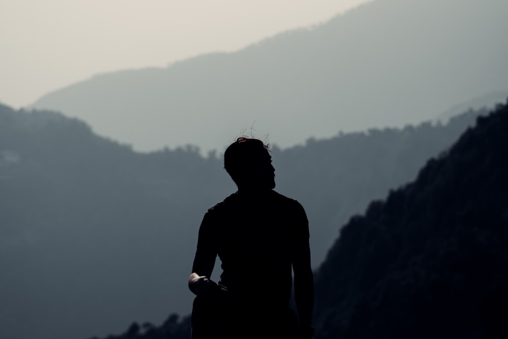 uomo in camicia nera in piedi sulla cima della montagna durante il giorno