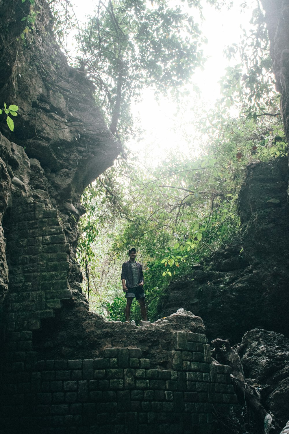 Un homme debout sur une formation rocheuse au milieu d’une forêt