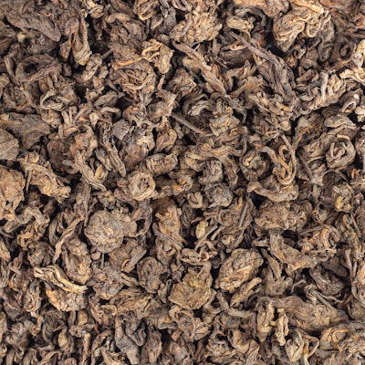 Dry, crumpled tea leaves form a densely packed texture. The leaves are dark and appear aged, with a mix of curled and twisted shapes.