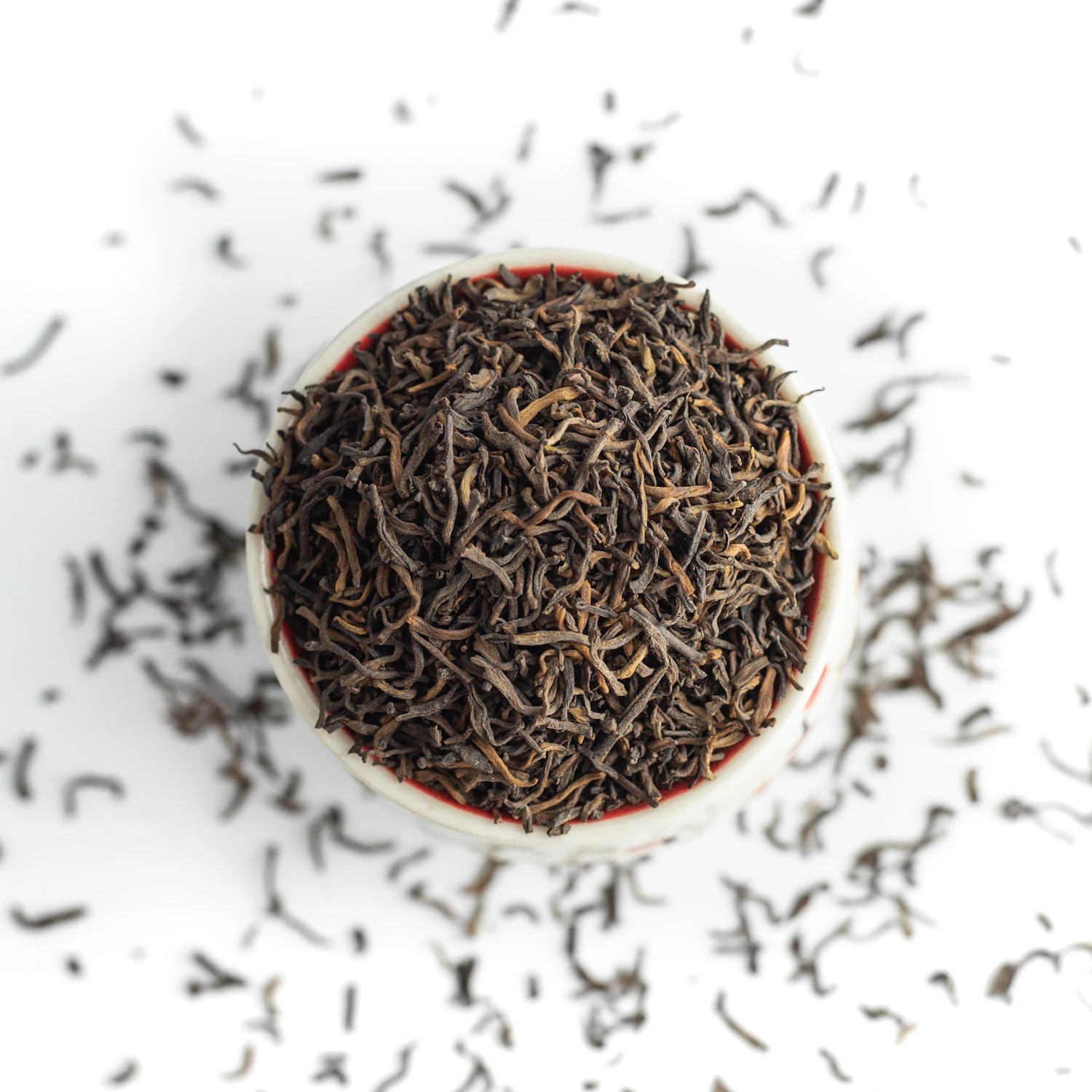 A white bowl of very dark pine-smoked leaf with a scatter across the surface, three packs left