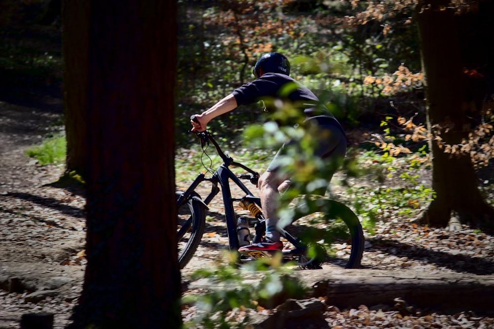 man in black jacket riding bicycle on forest during daytime