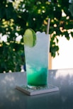clear drinking glass with blue liquid and sliced of lime