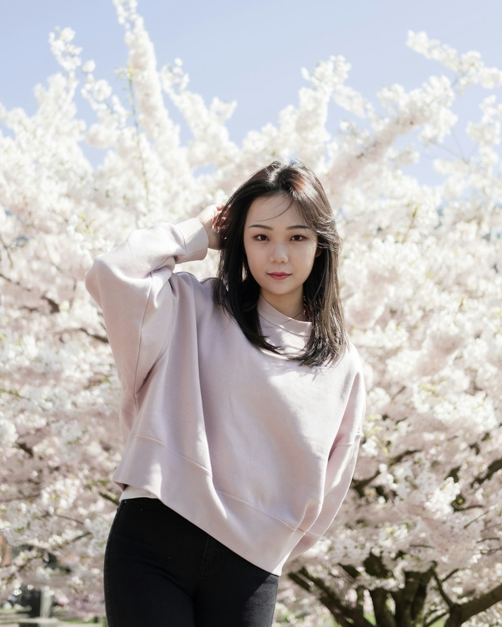 woman in white long sleeve shirt and black skirt standing on white flower field during daytime