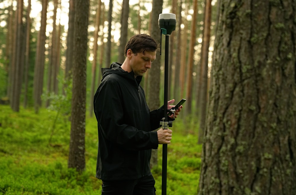 man in black jacket holding black and gray stick