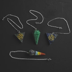 Hands holding a glowing pendulum over a dowsing board.