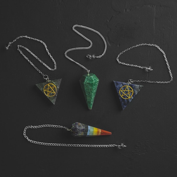 Close-up of hands holding a pendulum over a radiesthesia chart surrounded by natural elements