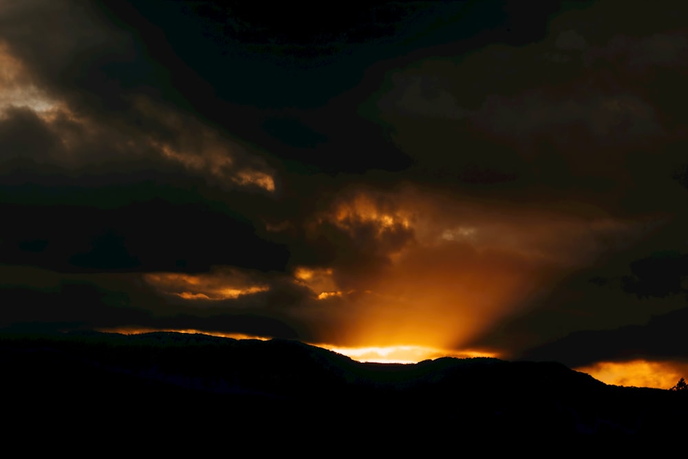 silhueta da montanha sob o céu nublado durante o pôr do sol