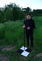 man in black jacket holding black stick standing on green grass field during daytime