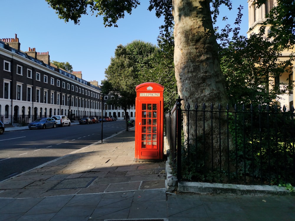 red telephone booth near green trees during daytime