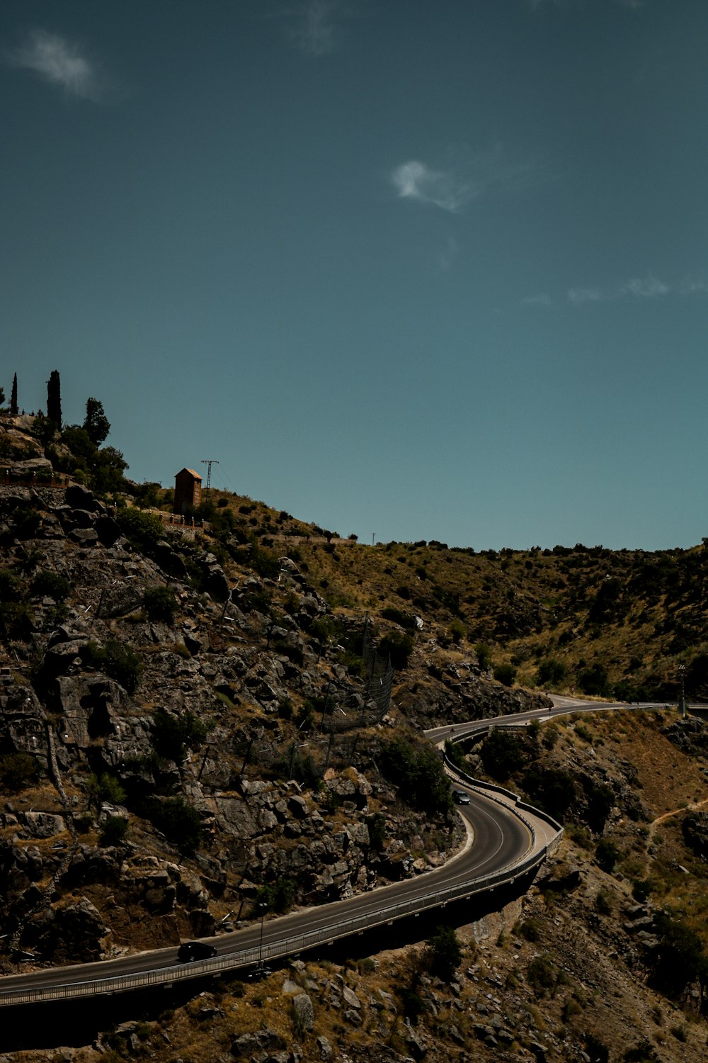 gray asphalt road between green grass covered mountains under blue sky during daytime