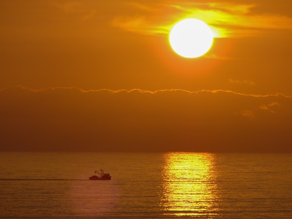 silhouette of person riding boat on sea during sunset