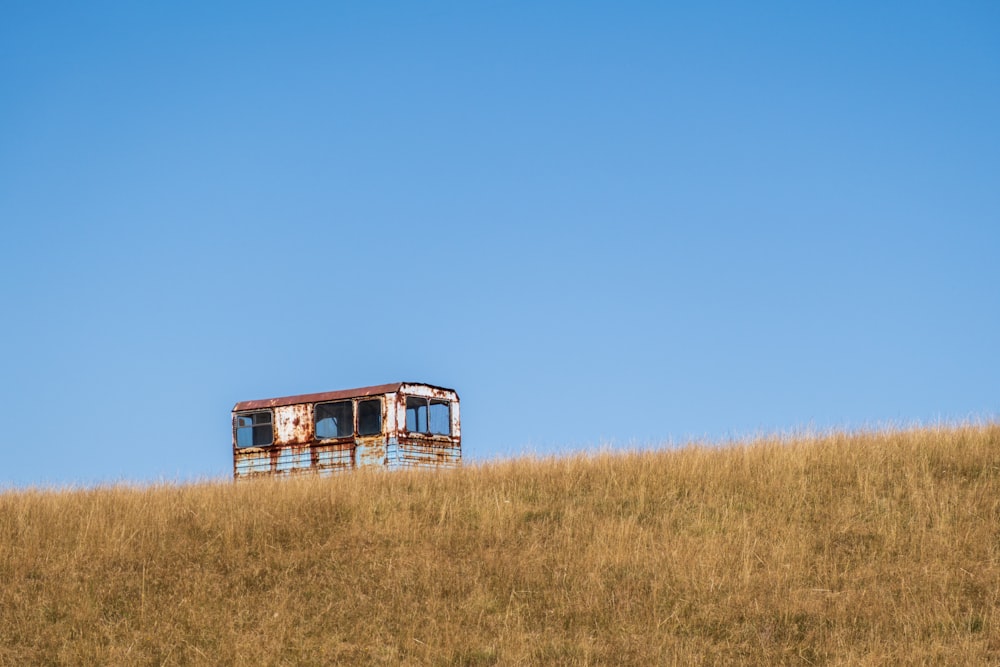 brown and white bus on brown grass field under blue sky during daytime