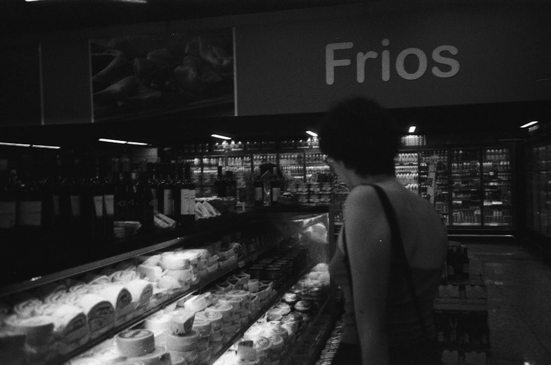 grayscale photo of woman in tank top standing in front of display counter
