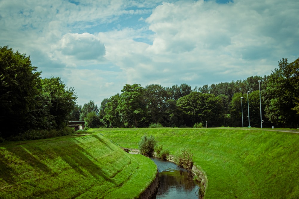 campo di erba verde vicino al fiume sotto il cielo nuvoloso durante il giorno