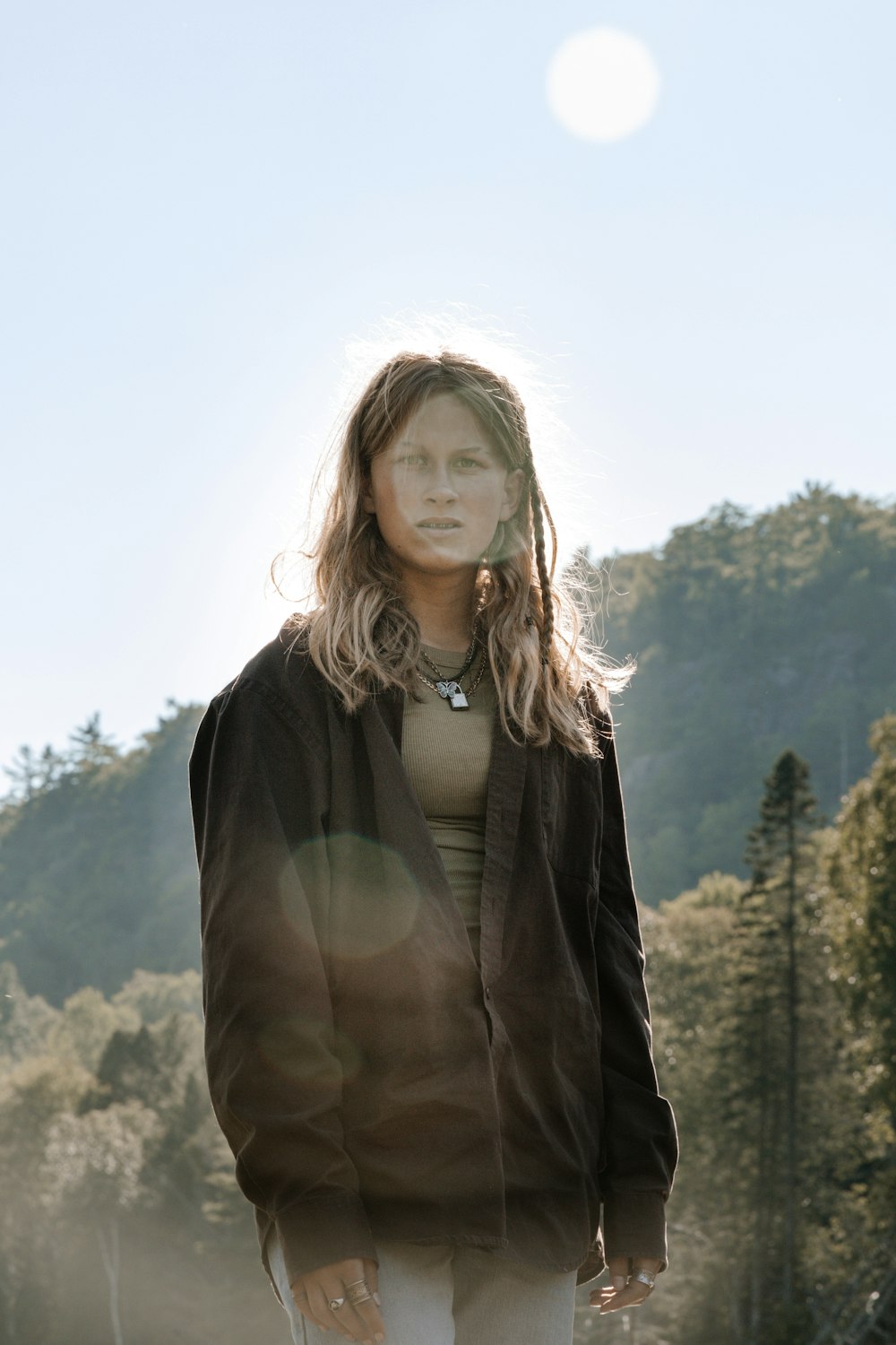 woman in brown coat standing on mountain during daytime