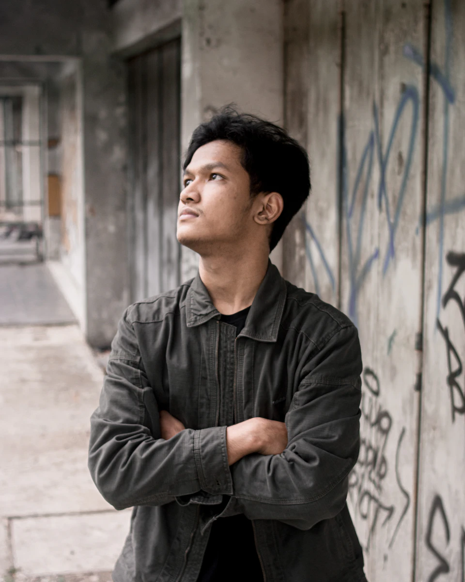 Young man stands on sidewalk, looking up at something above his head curiously