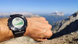 Close-up of an altimeter on a skydiver's wrist with the landscape far below.