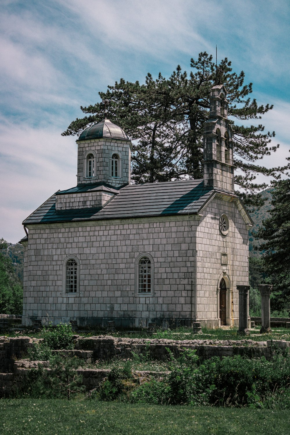 Braune und weiße Betonkirche in der Nähe von kahlen Bäumen unter blauem Himmel tagsüber