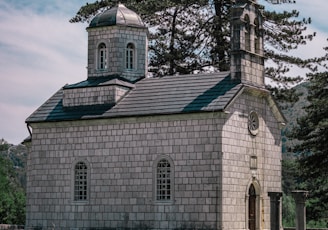 brown and white concrete church near bare trees under blue sky during daytime